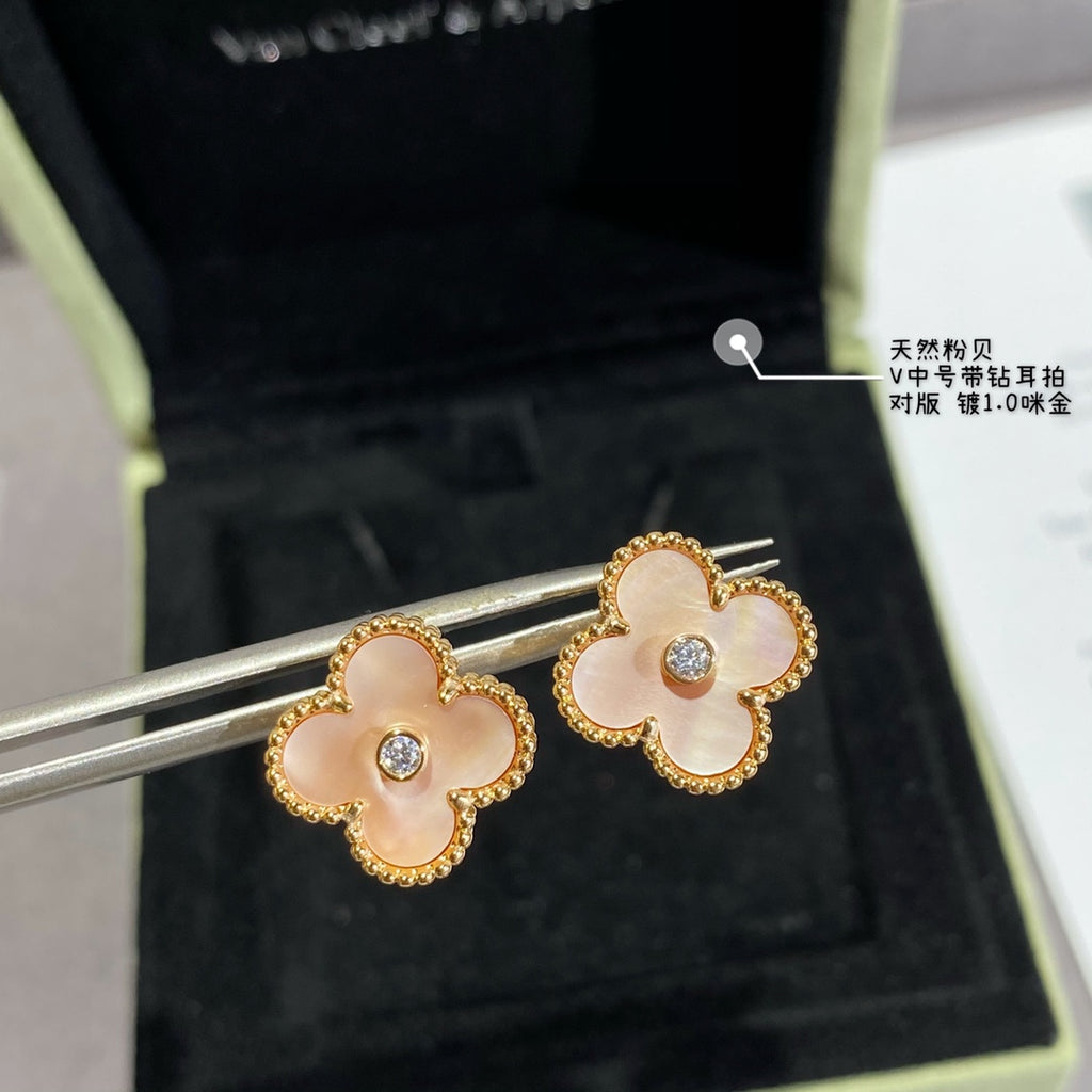Gold clover stud earrings with white enamel petals and clear round center stones on display