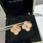 Gold clover stud earrings with white enamel petals and clear round center stones on display