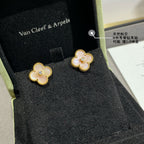 Gold clover stud earrings with white enamel petals and a round clear center stone in box