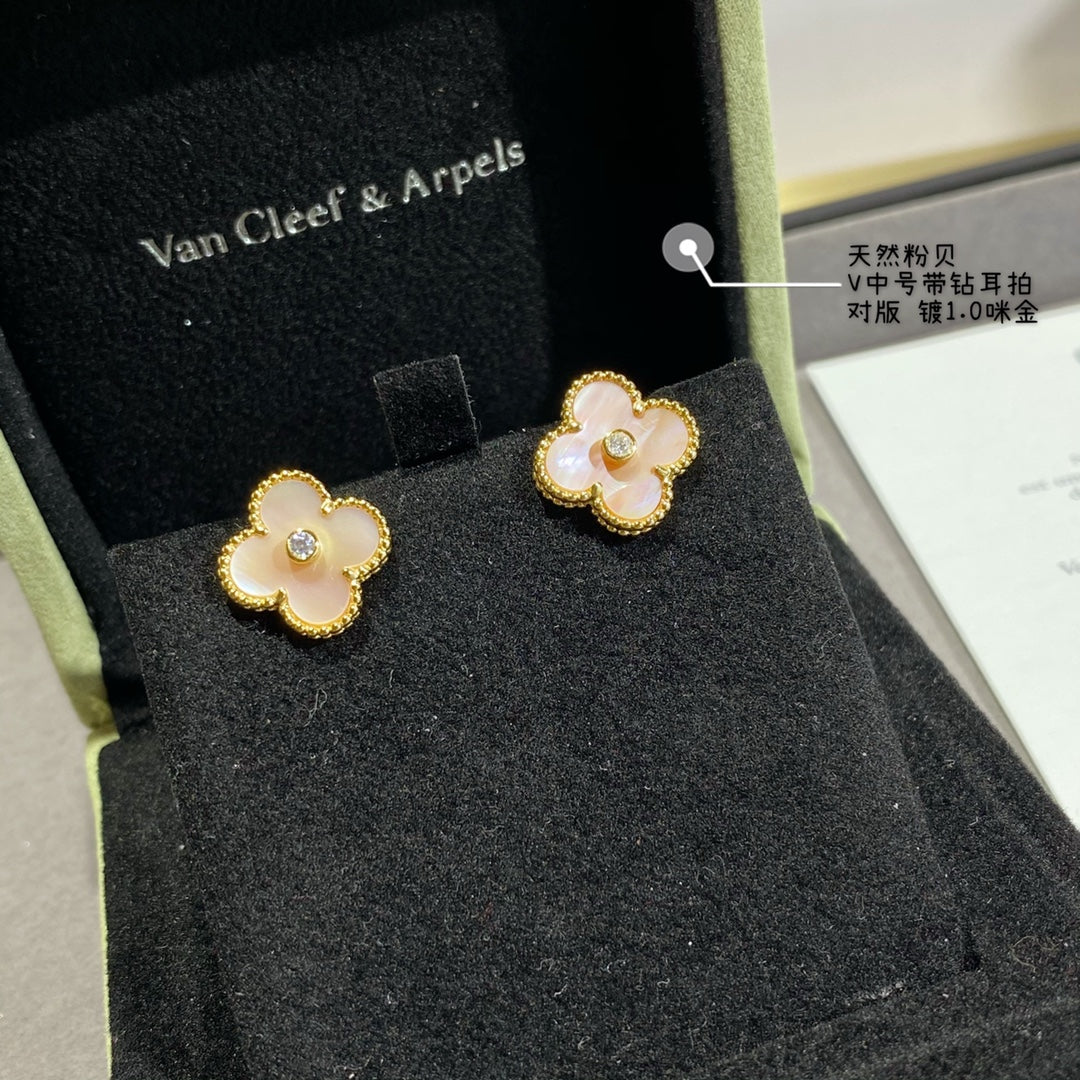 Gold clover stud earrings with white enamel petals and a round clear center stone in box