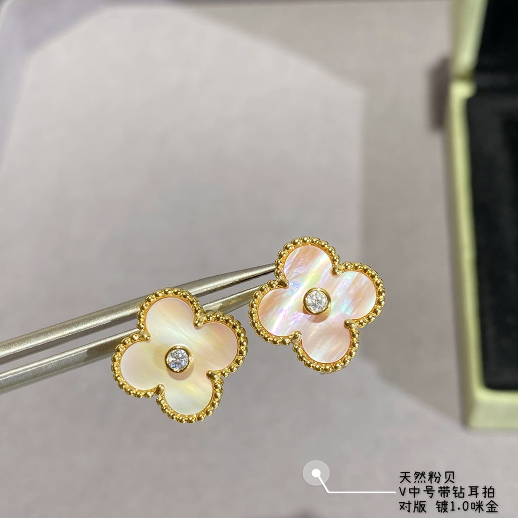 Gold clover stud earrings with white enamel petals and clear center stones on earring posts