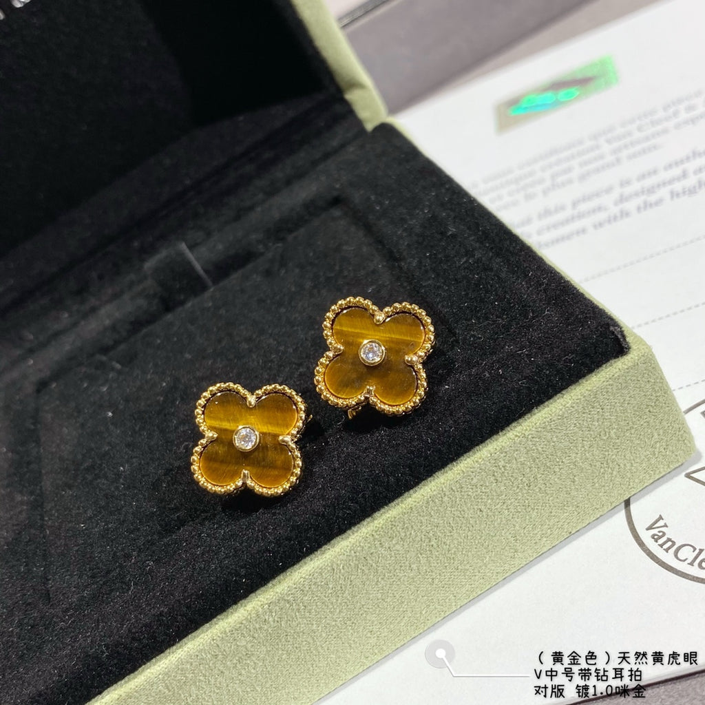 Gold clover stud earrings on display, yellow enamel with central round crystal