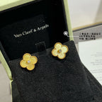 Gold clover stud earrings with small clear stone centers, on display in a jewelry box.