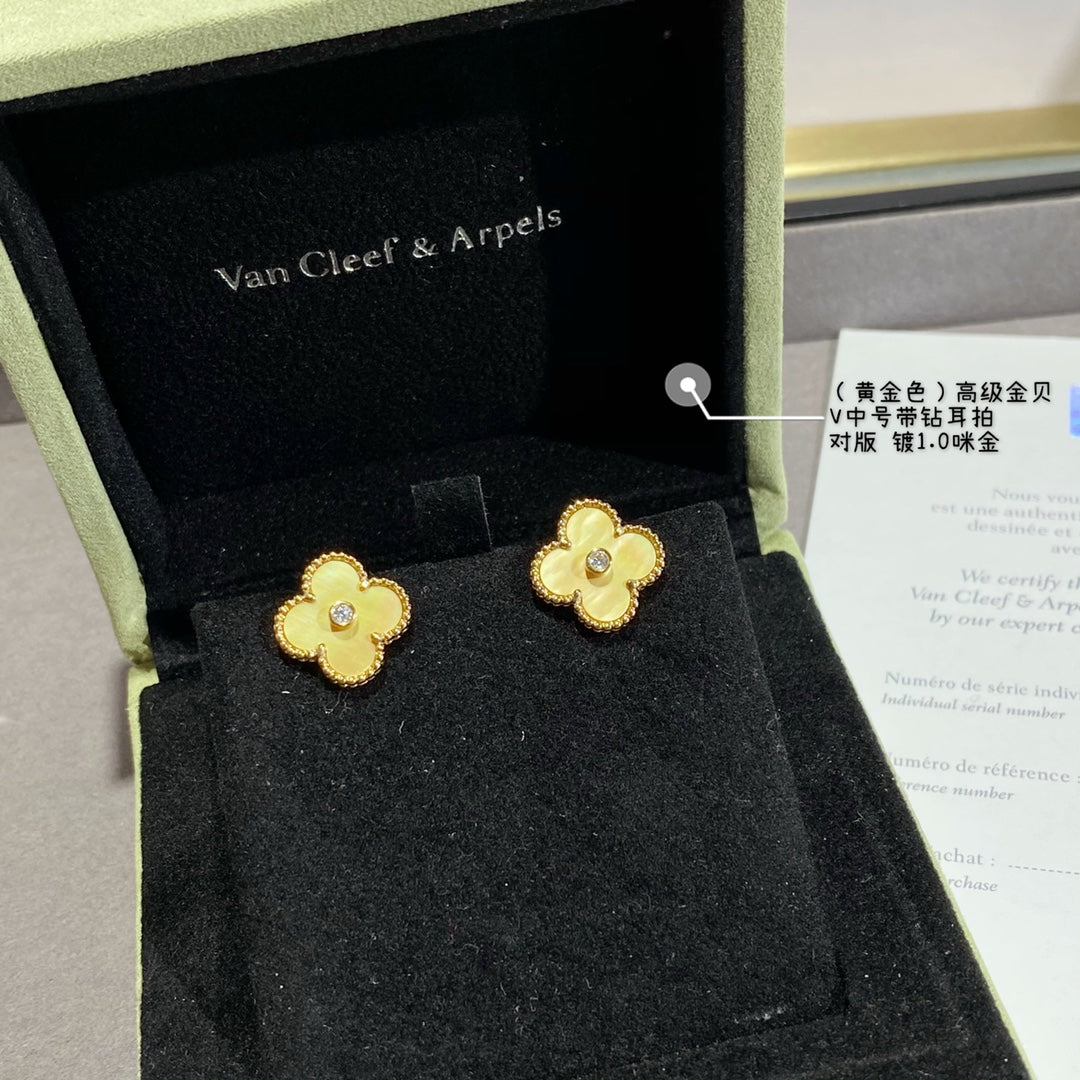 Gold clover stud earrings with clear center stones, two earrings in a box.