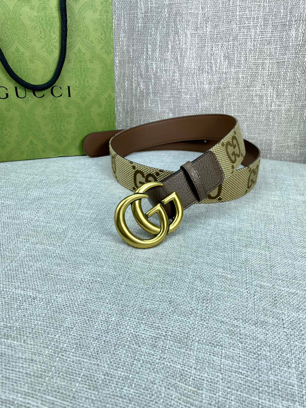 Gucci belt with beige GG canvas strap and gold double-G buckle on dark brown leather