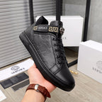 Black Versace high-top sneakers in hand; lace-up with logo strap detail