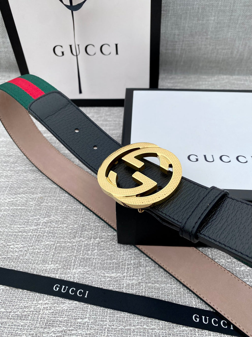 Black leather belt with large gold GG buckle and green-red web stripe