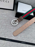Gucci belt with brown leather strap, silver-tone double G buckle, and green-red stripe web edge.