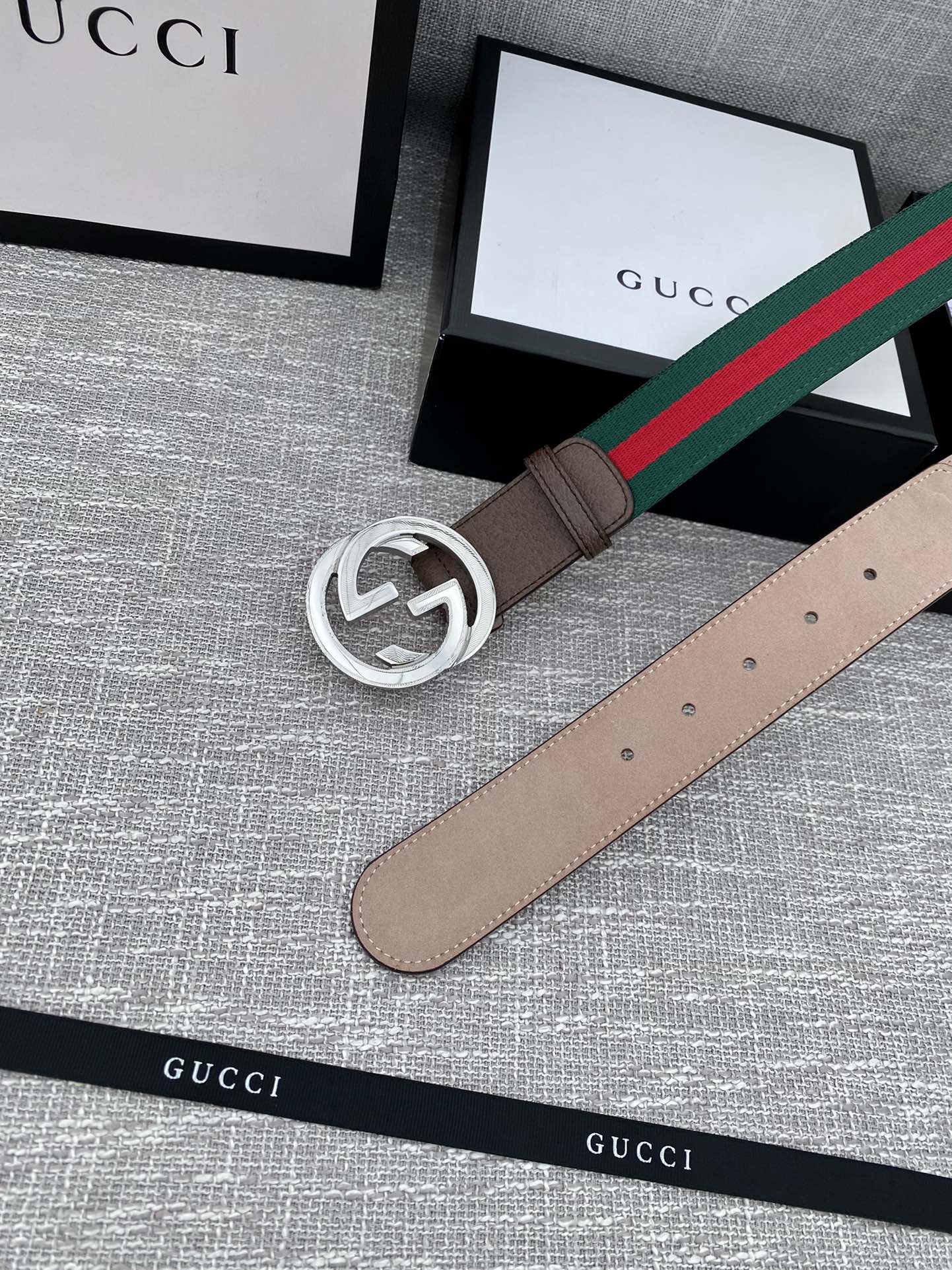 Gucci belt with brown leather strap, silver-tone double G buckle, and green-red stripe web edge.
