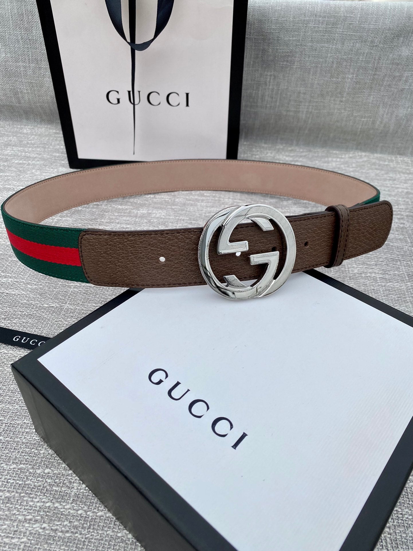 Gucci belt with brown leather strap, silver-tone double G buckle, and green-red stripe web trim.