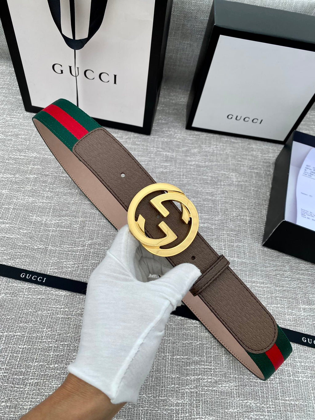 Gucci belt with brown leather strap, gold-tone double G buckle, and green-red web stripe trim.
