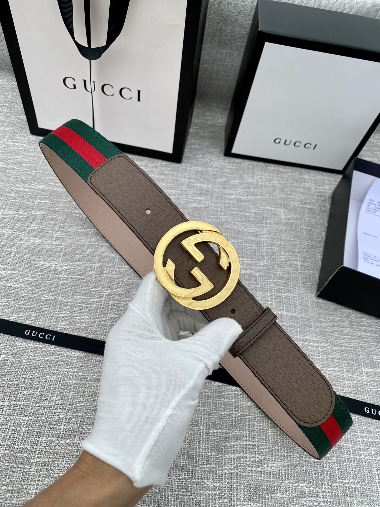 Gucci belt with brown leather strap, gold-tone double G buckle, and green-red web stripe trim.