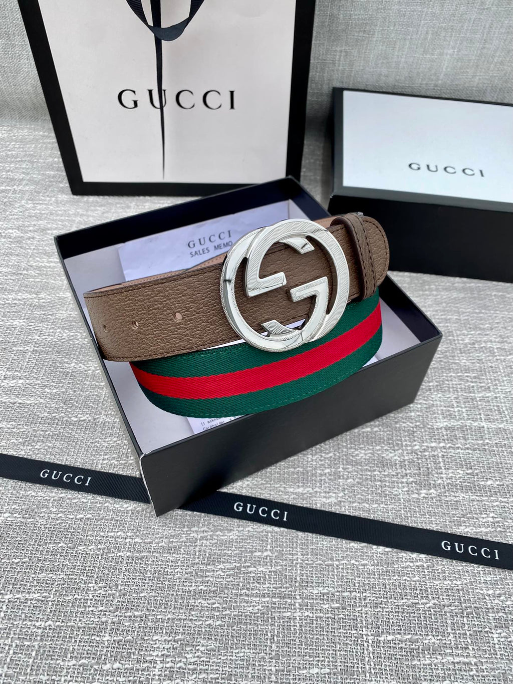 Gucci belt featuring brown leather strap, silver double G buckle, and green-red web stripe.