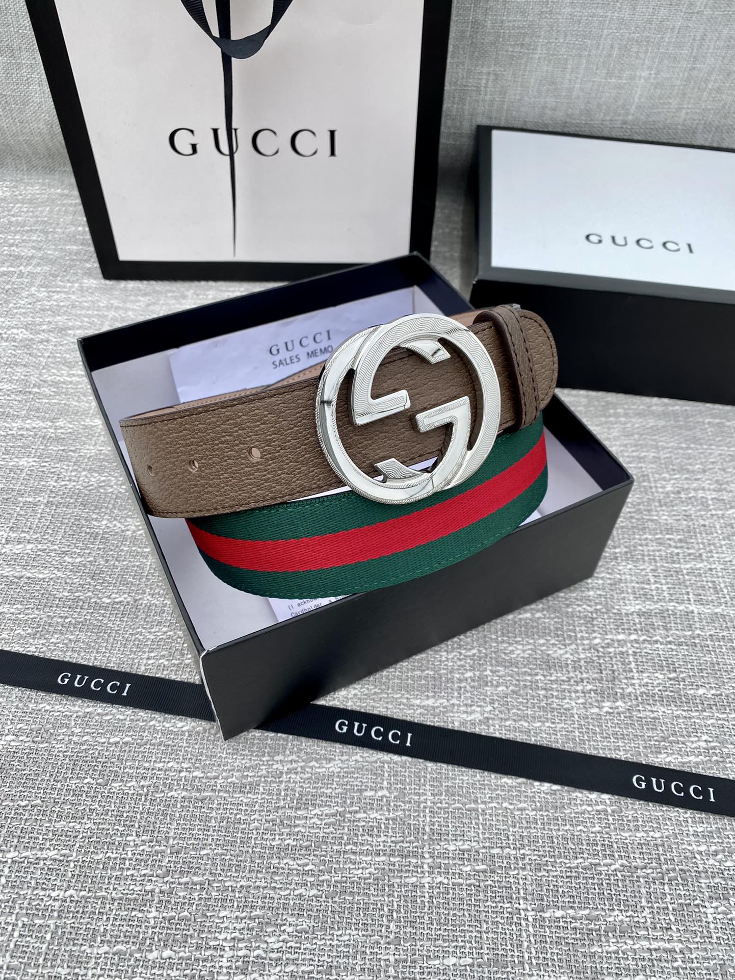 Gucci belt featuring brown leather strap, silver double G buckle, and green-red web stripe.