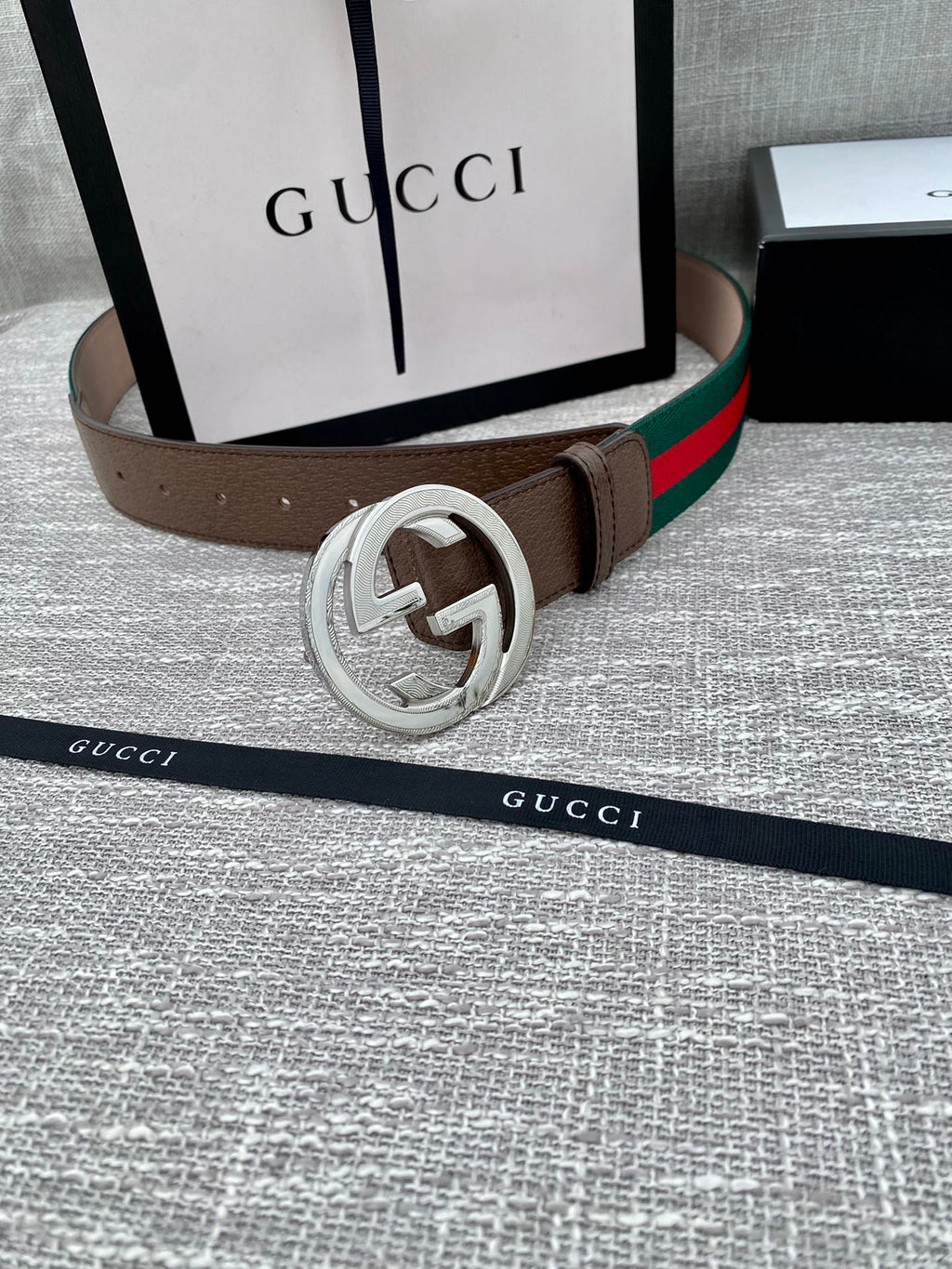 Gucci belt with brown leather strap, silver-tone double G buckle, and green-red web stripe.