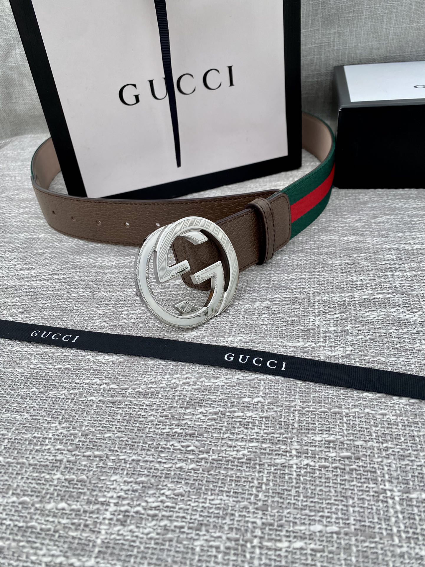 Gucci belt with brown leather strap, silver-tone double G buckle, and green-red web stripe.