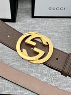 Gucci belt detail: brown leather strap with gold-tone double G buckle, no stripe visible.