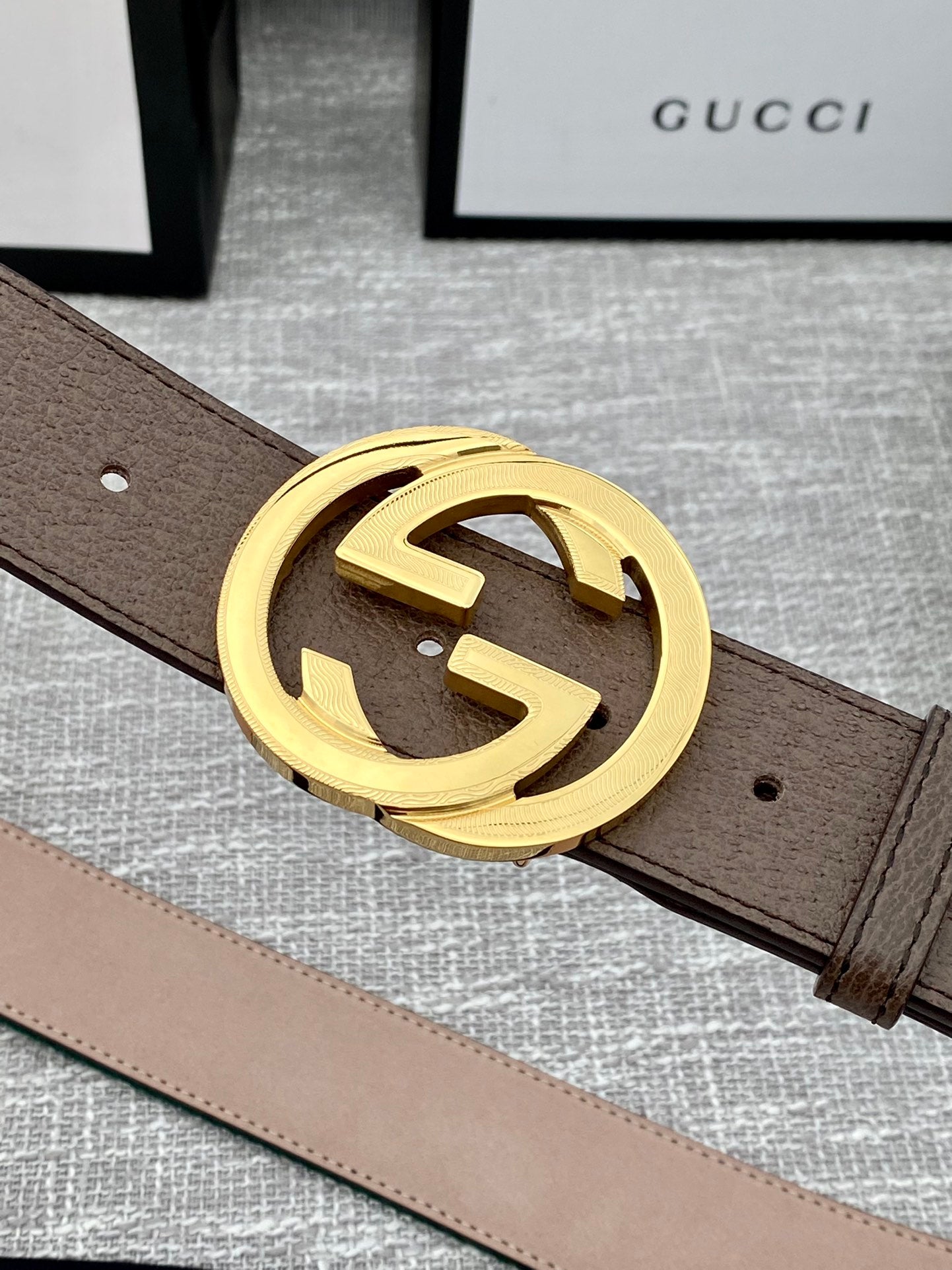 Gucci belt detail: brown leather strap with gold-tone double G buckle, no stripe visible.