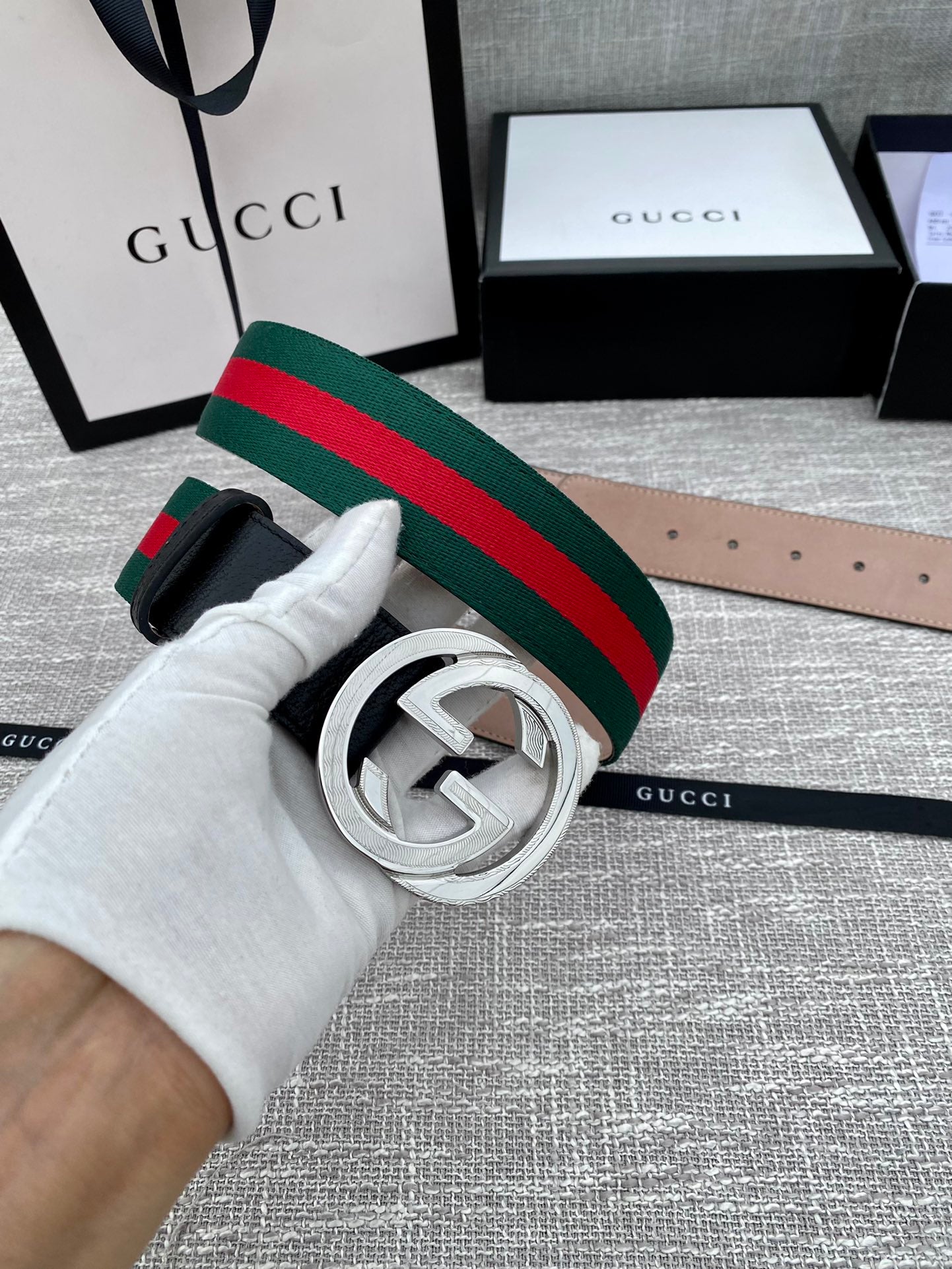 Black leather belt with silver-tone GG buckle and green-red web stripe close-up