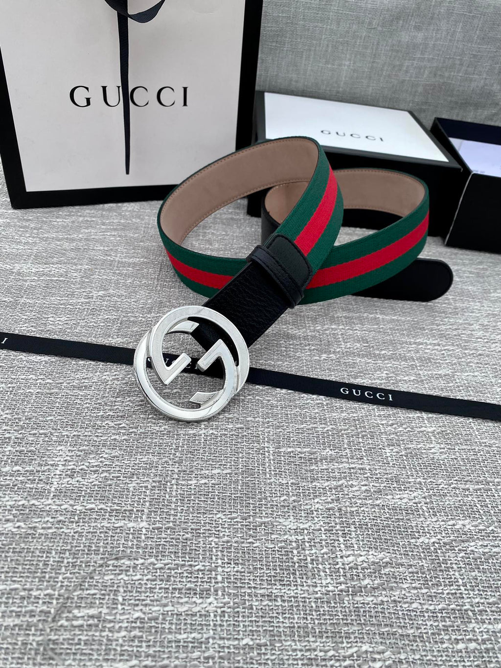Black leather belt with silver-tone GG buckle and green-red web stripe, laid out