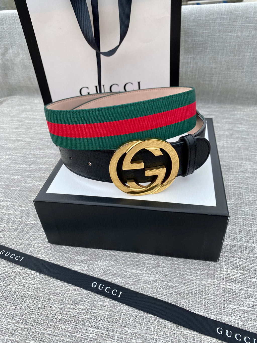 Black leather belt with gold-tone GG buckle and green-red web stripe on box