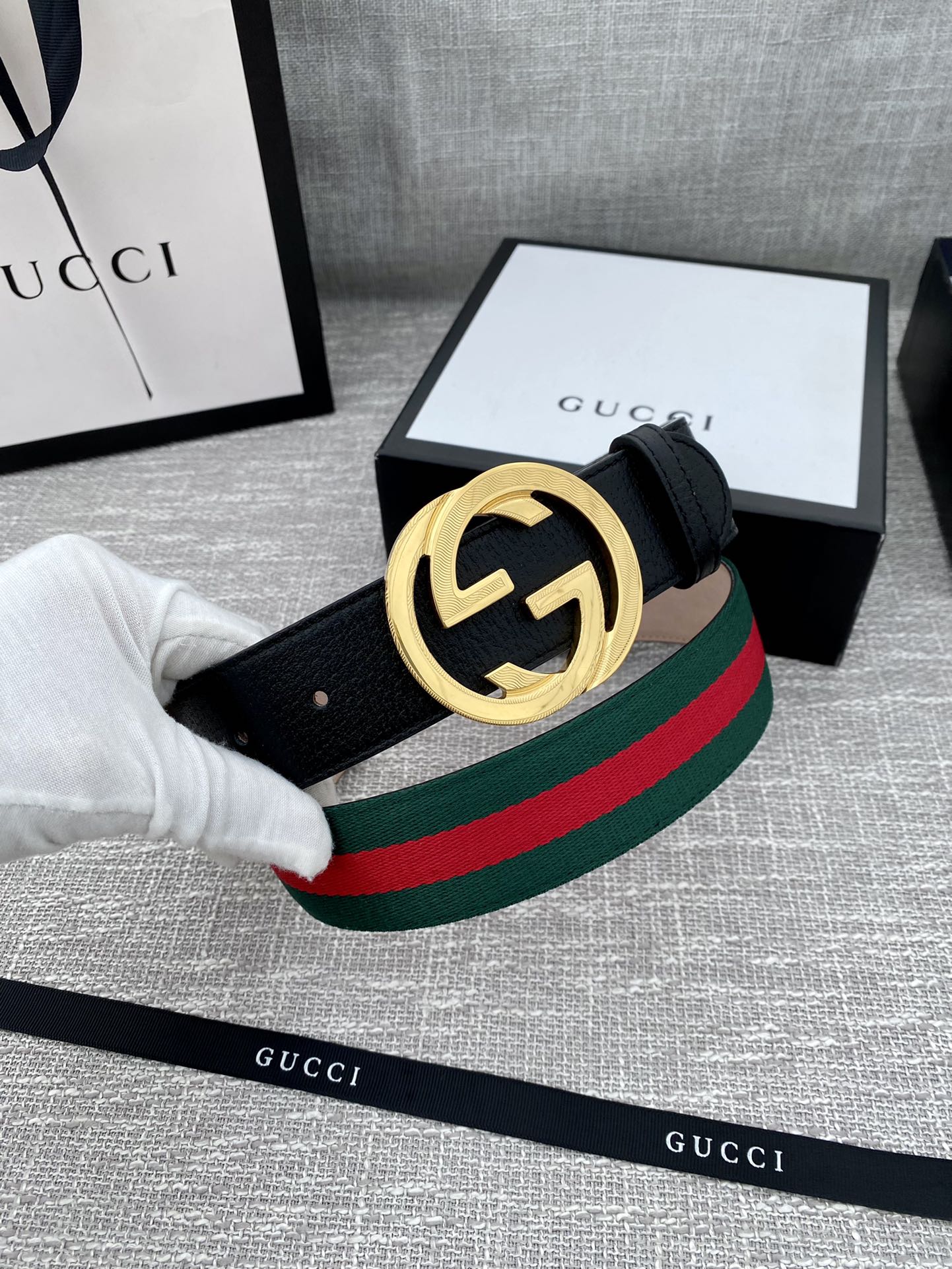 Black leather belt with gold-tone GG buckle, worn strap shows green-red stripe