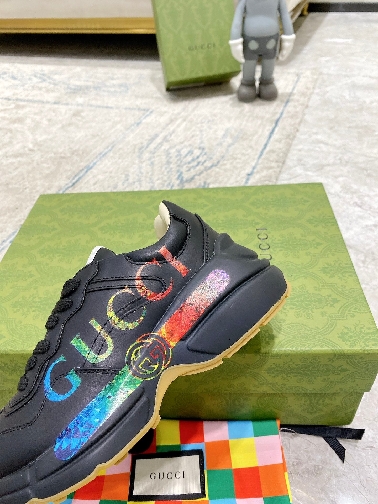 Black Gucci low-top sneaker with multicolor web logo on side and gum sole