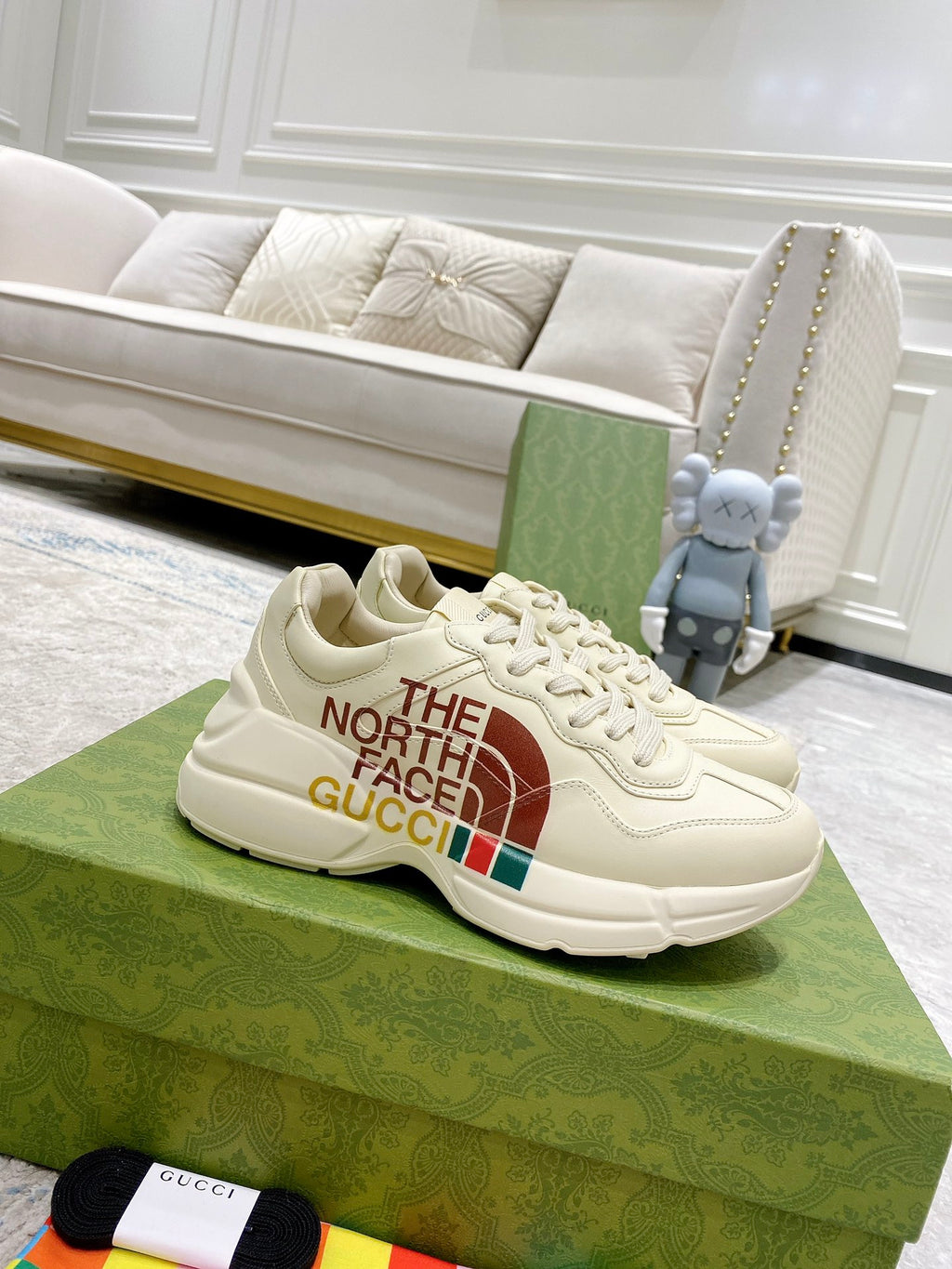 White low-top sneaker with laces, side graphic reading “THE NORTH FACE GUCCI”.