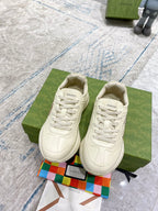 White lace-up sneakers, front view on green box with “GUCCI” label.
