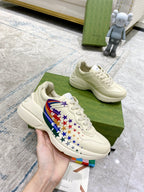 White lace-up sneaker held in hand, multicolor star and flag side panel