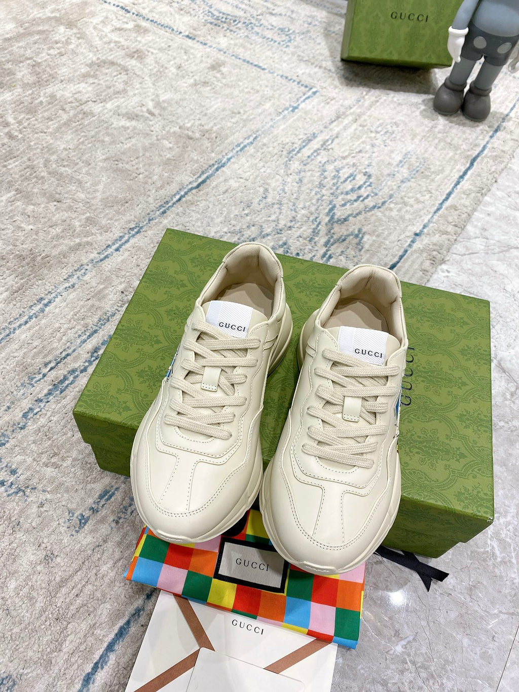 Pair of white Gucci unisex lace-up sneakers on green box