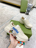 White Gucci unisex lace-up sneakers with 'FLASH' graphic, held in hand