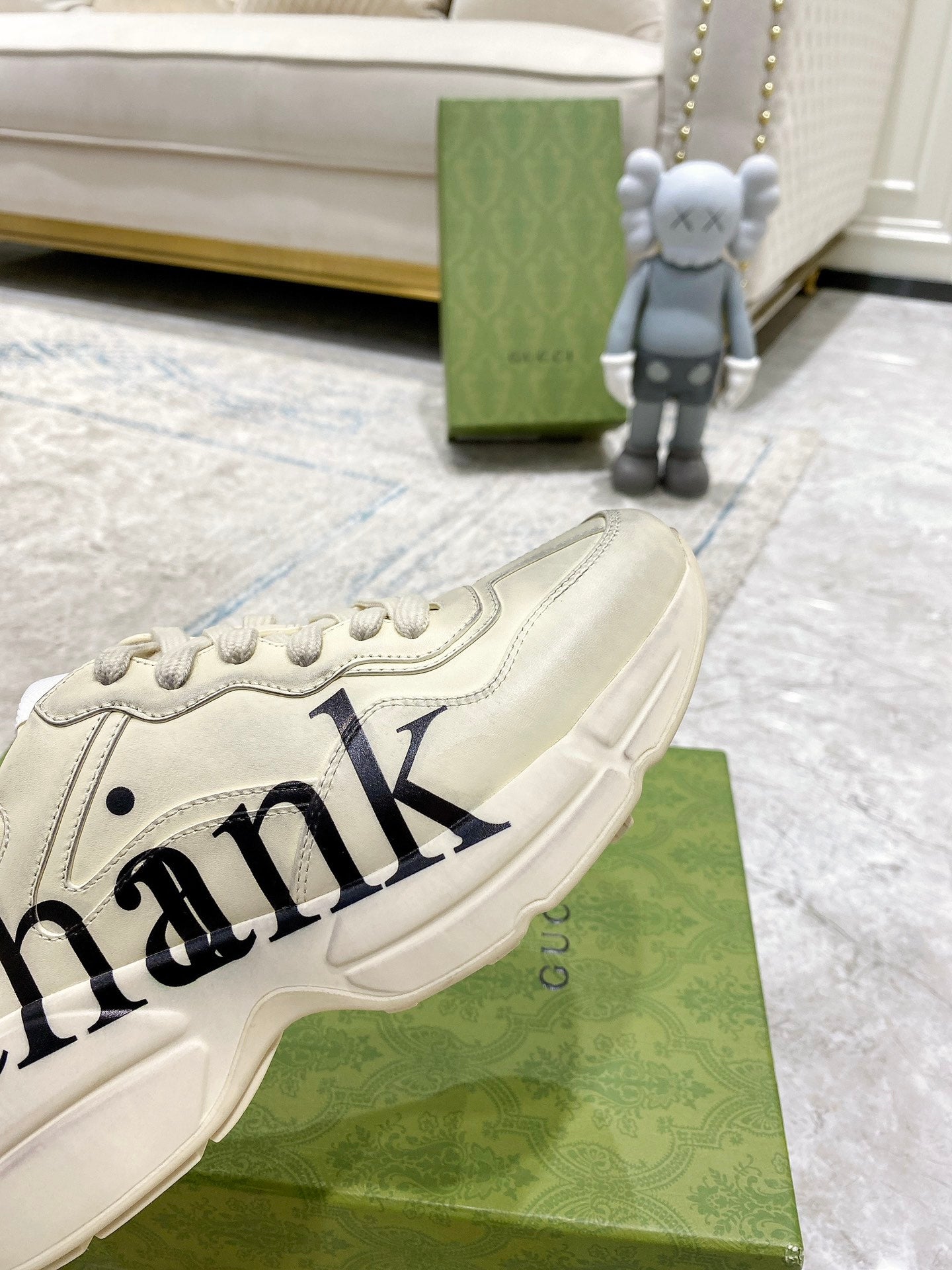 Cream Gucci unisex sneakers close-up with large 'ank' logo on side panel