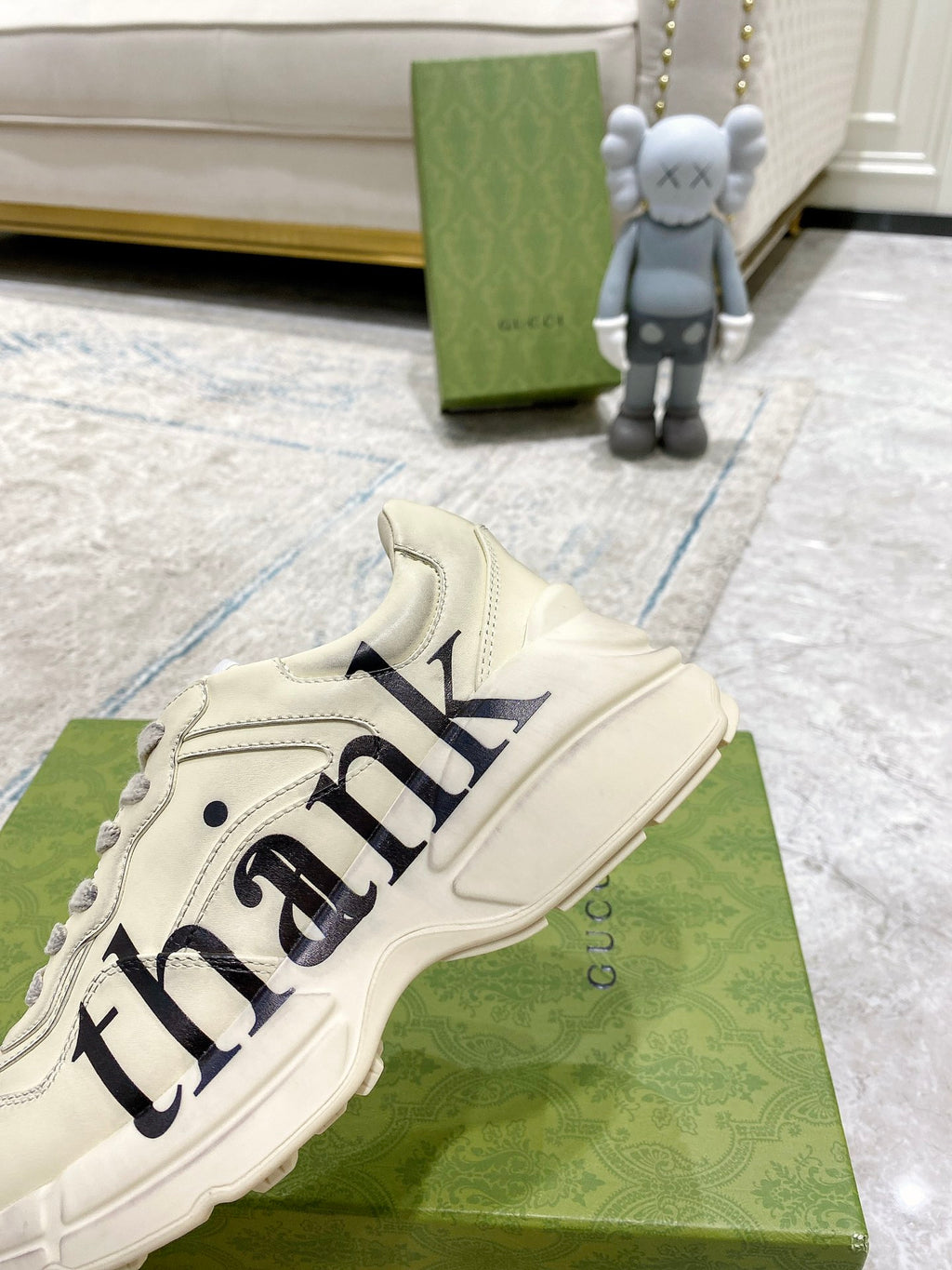 Cream Gucci unisex sneakers close-up with 'thank' script, lace-up and logo