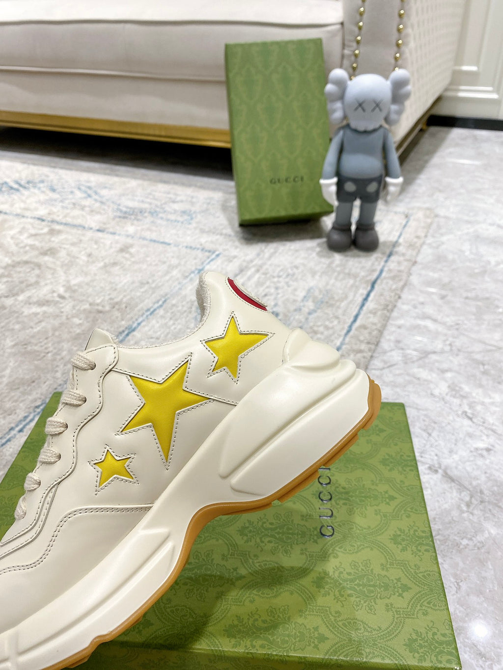 Gucci unisex sneakers close-up, white upper with gold star patchwork design