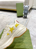 Gucci unisex sneakers close-up, white upper with gold star patchwork design