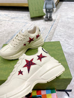 Gucci unisex white sneakers with red star patches, stacked on shoebox
