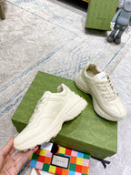 Cream Gucci sneakers on green box, showing laces and cushioned thick sole.