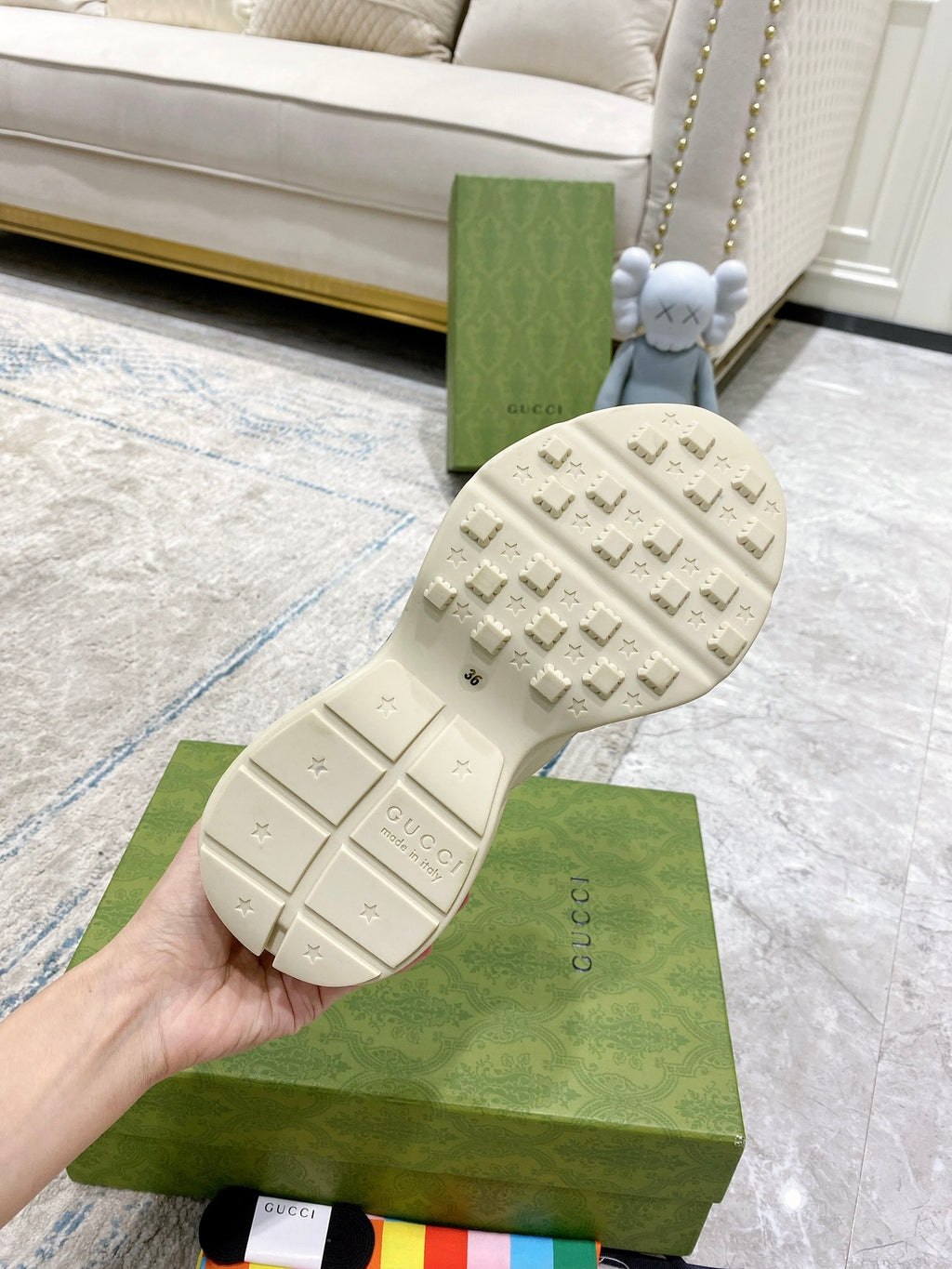 Cream Gucci sneaker outsole tread with branding marks, shown from bottom.