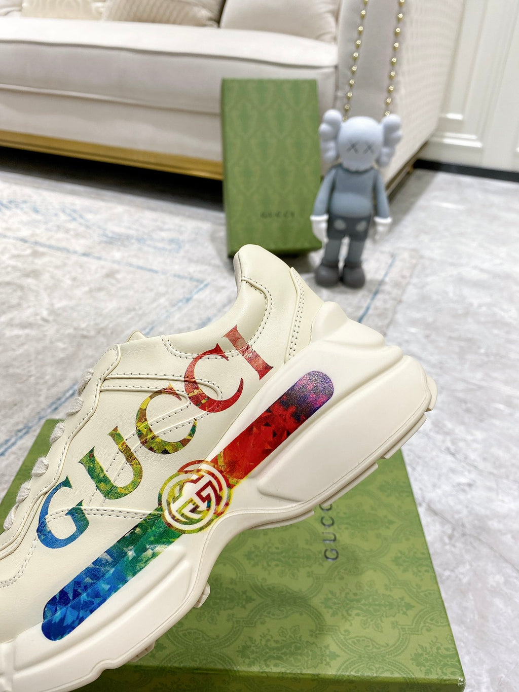 Gucci unisex luxury sneaker side view, white upper with multicolor logo stripe