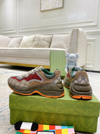 Gucci GG sneakers, front view: red side panels, white laces, green lining, orange sole