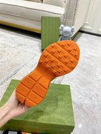 Gucci sneaker outsole close-up, orange rubber tread with embossed logos