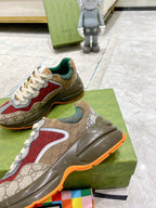 Gucci GG sneakers on green box, side view: red panel, white laces, orange outsole