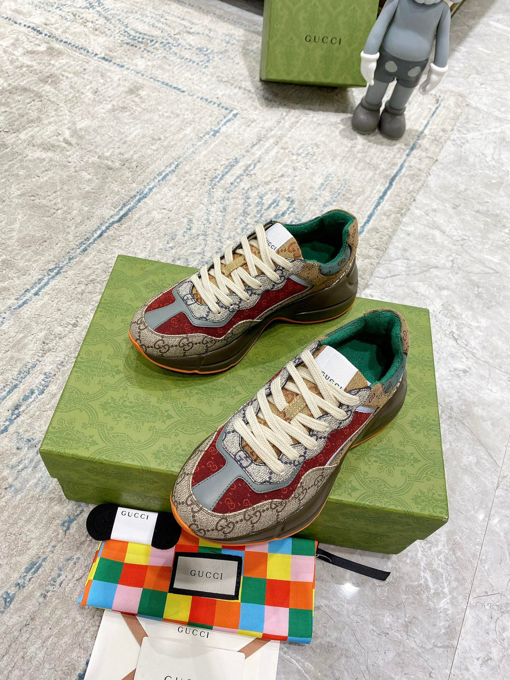 Gucci sneaker pair on box: beige GG canvas, red details, white laces, green inner lining