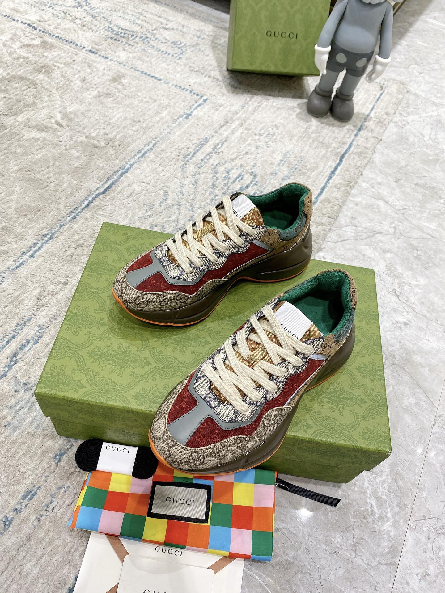 Gucci sneaker pair on box: beige GG canvas, red details, white laces, green inner lining