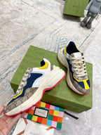 Gucci unisex sneakers held in hand: cream, navy, and yellow panels with GG detail