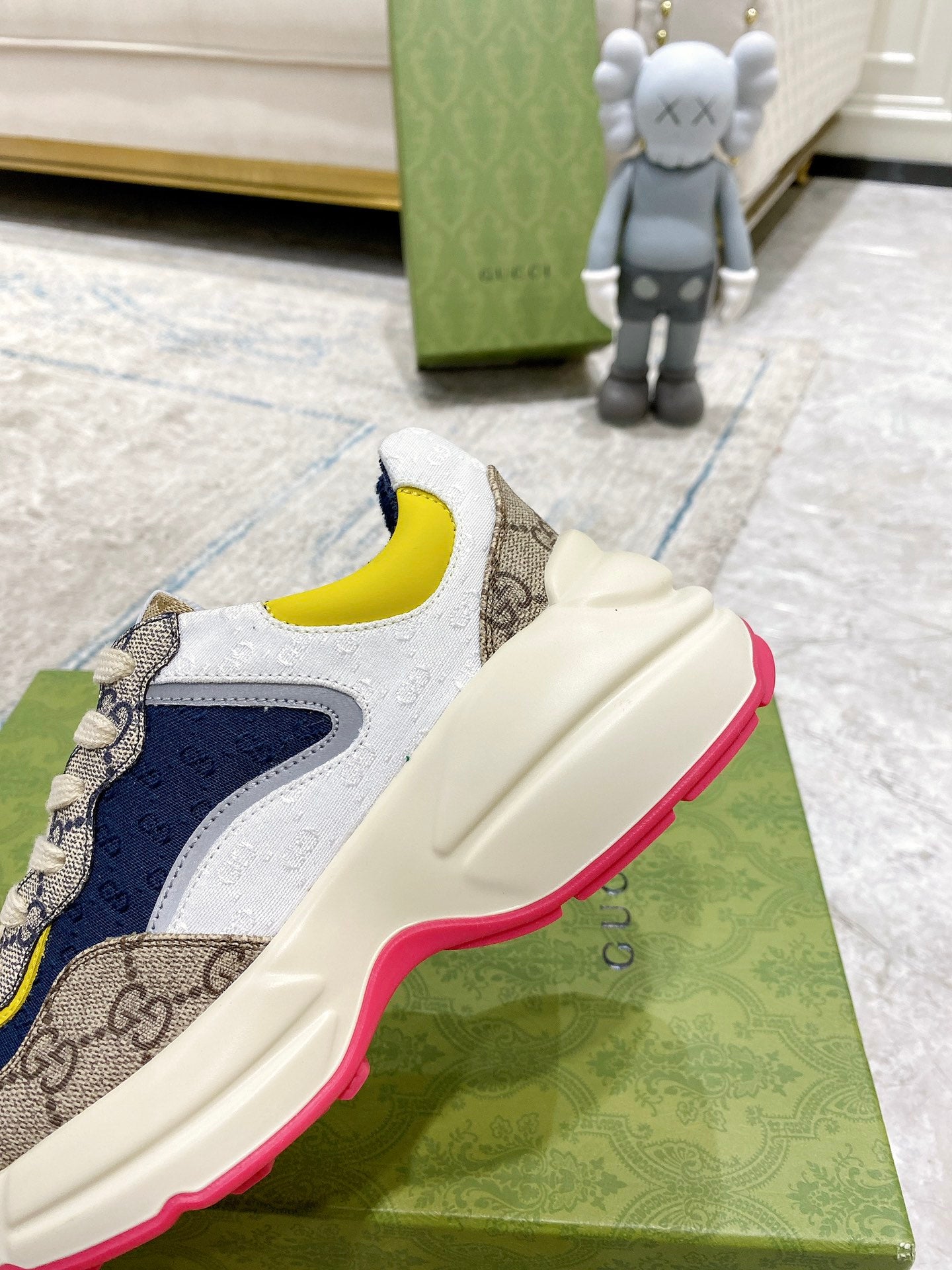Gucci unisex sneaker close-up, side profile: cream leather with navy and yellow accents