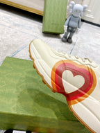 White Gucci unisex sneaker side view with heart graphic band and gum sole