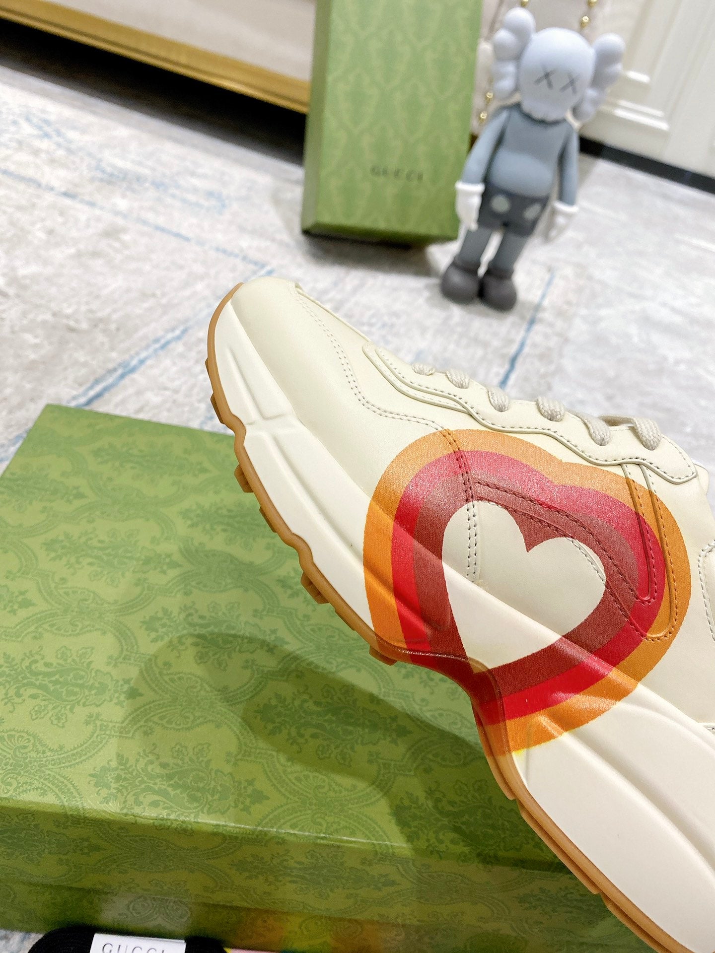 White Gucci unisex sneaker side view with heart graphic band and gum sole