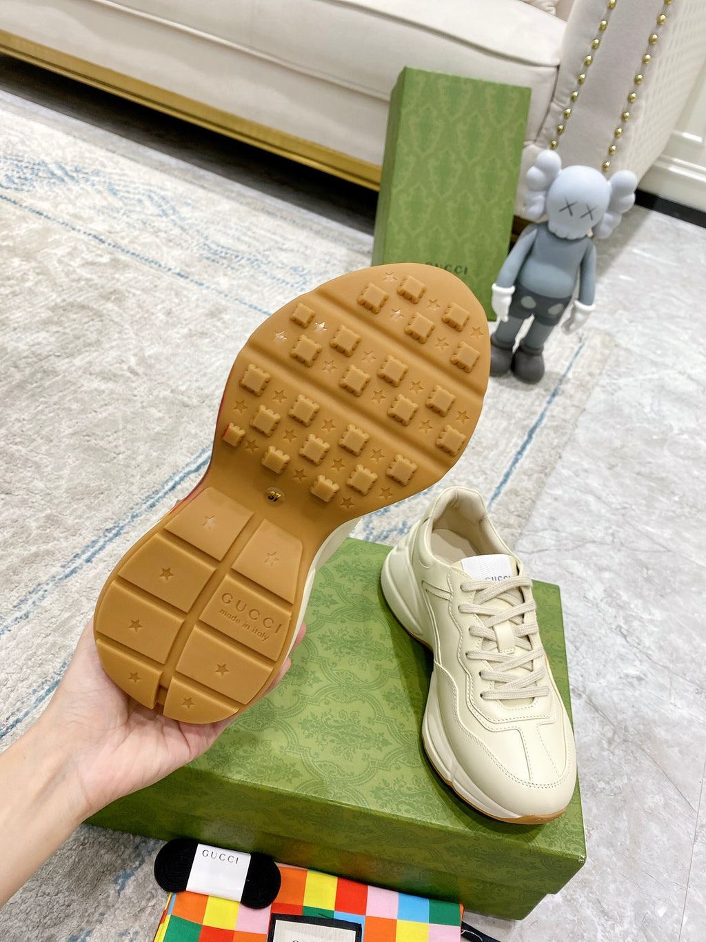 White Gucci unisex sneaker with textured gum outsole visible on green box